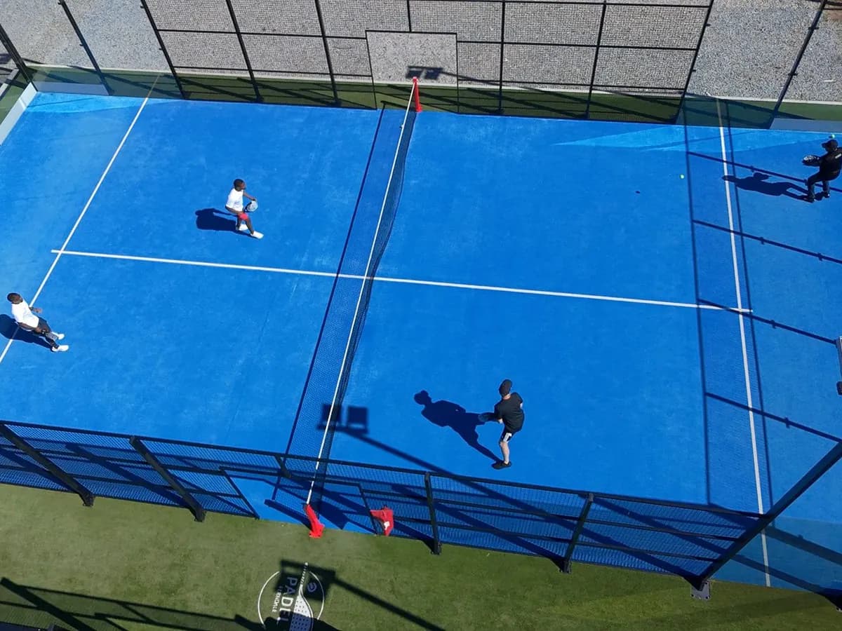 Match de double de padel vu du ciel, quatre joueurs sur un terrain extérieur